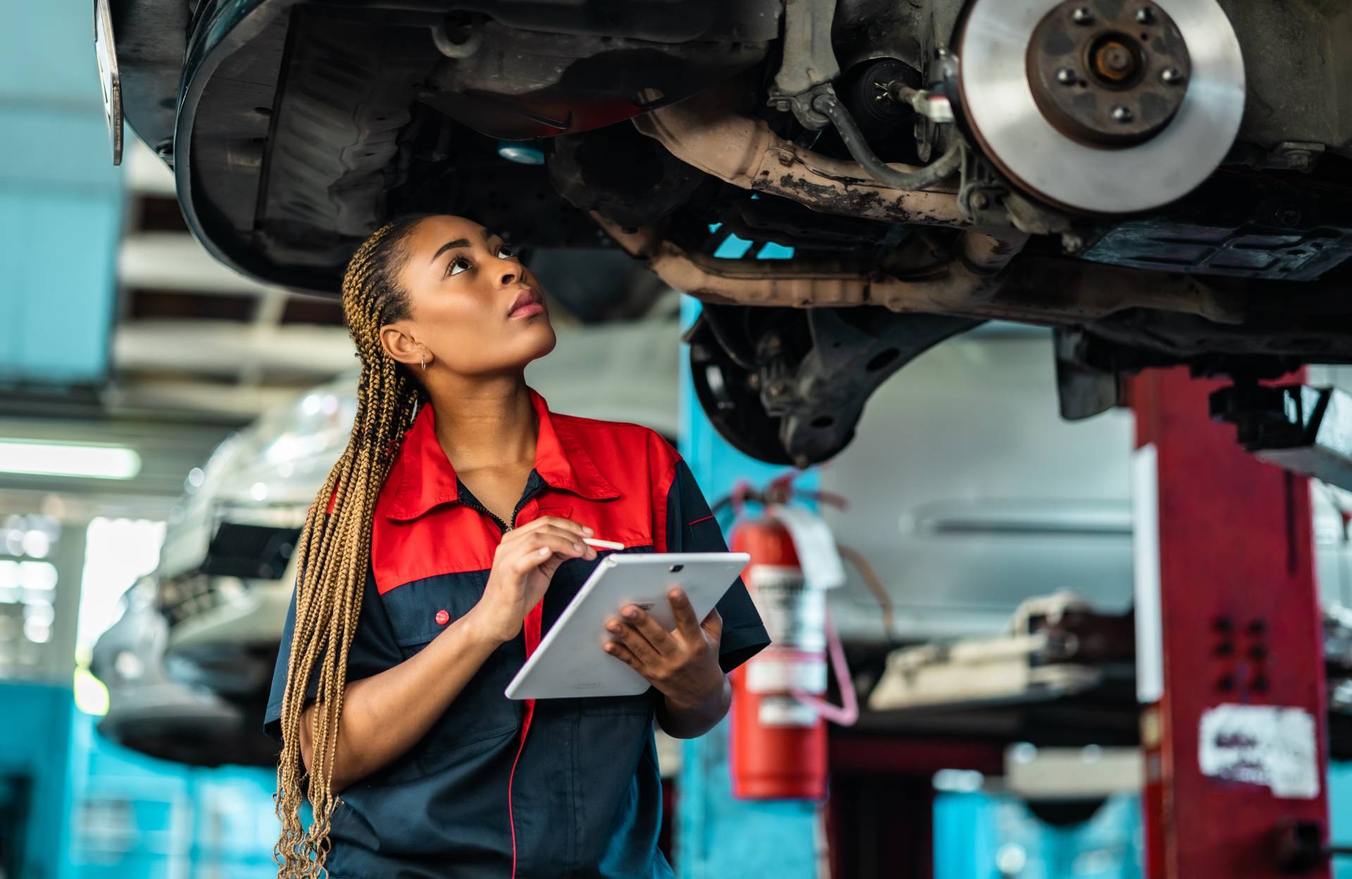 A mechanic looking at the underside of a vehicle